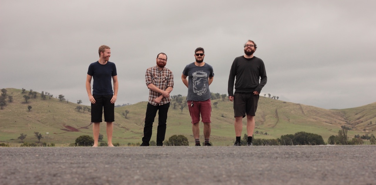 Four dishevelled blokes standing on the side of the highway